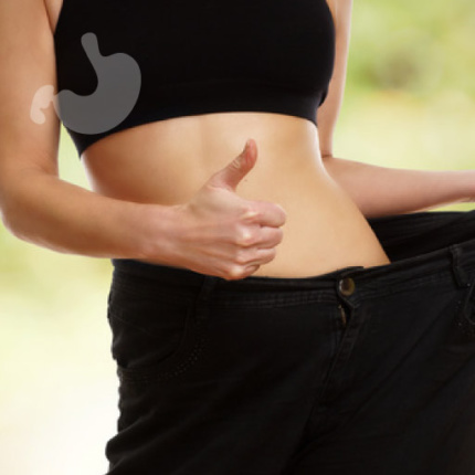 Leczenie otyłości, Gastromed, Scanmed, kobieta trzymająca kciuk w górę. Ubrana w zbyt duże spodnie